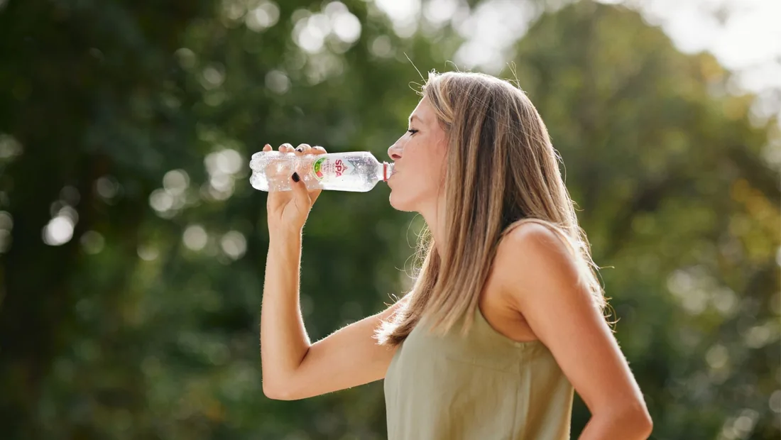 Vrouw drinkt uit een flesje Spa